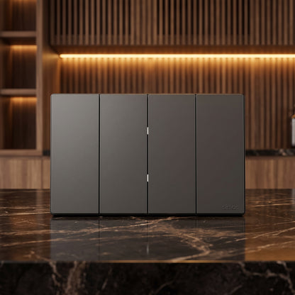 A four-panel dark gray smart wall switch panel with slim vertical handles, displayed on a polished black marble countertop in a modern kitchen setting with warm wood slat backsplash and under-cabinet lighting.